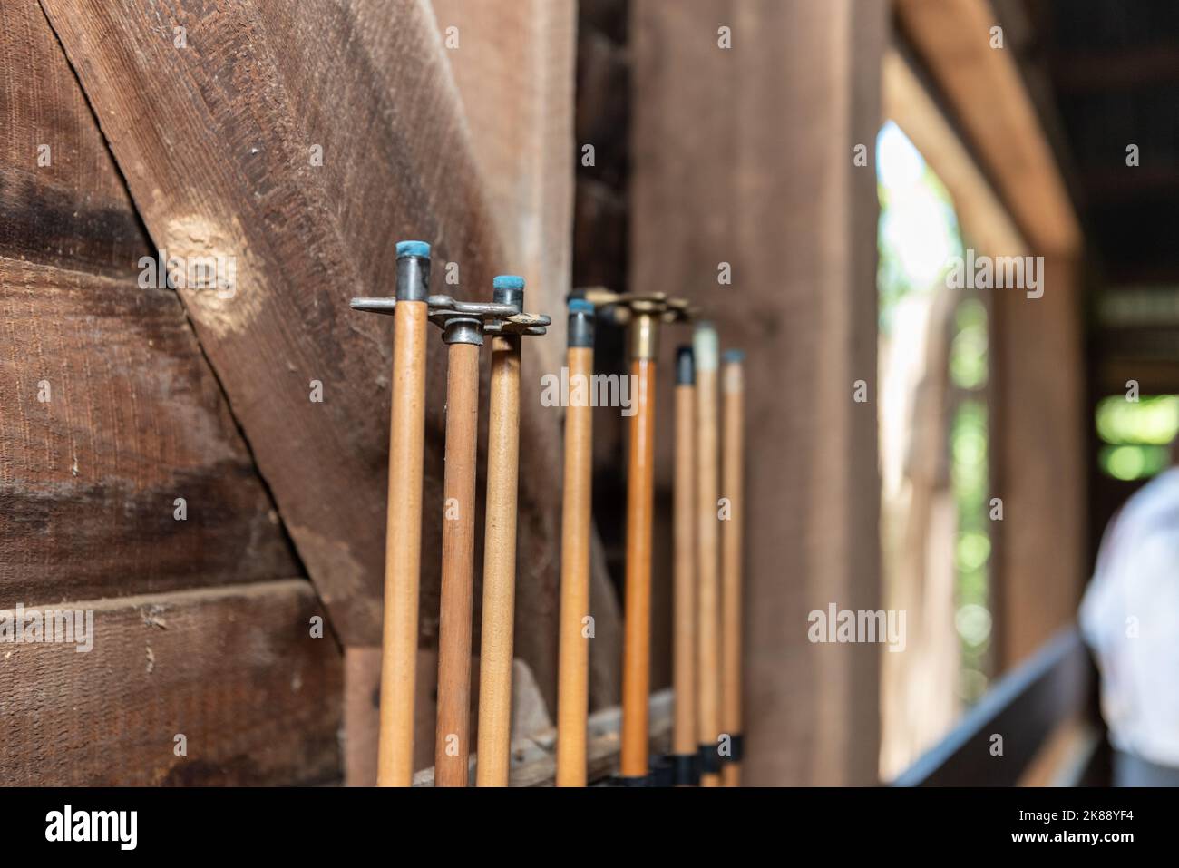 Blue tips of the pool cues are stored upright against the wooden barn wall. Stock Photo