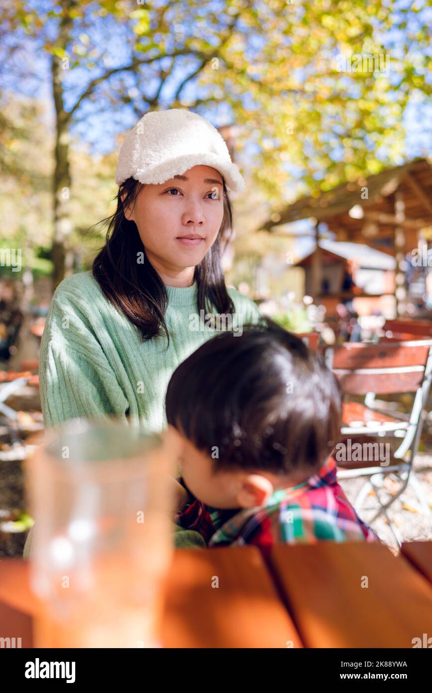 Mother and son at an outdoor cafe. It was autumn in Munich, Germany. The trees leaves were turning yellow in the background. Stock Photo