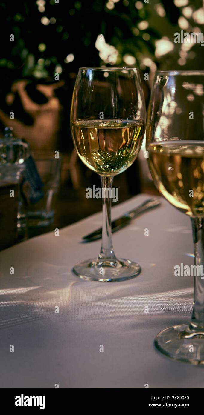 Reflection of the sun's rays and the surrounding space in a glass of white wine standing on a restaurant table Stock Photo