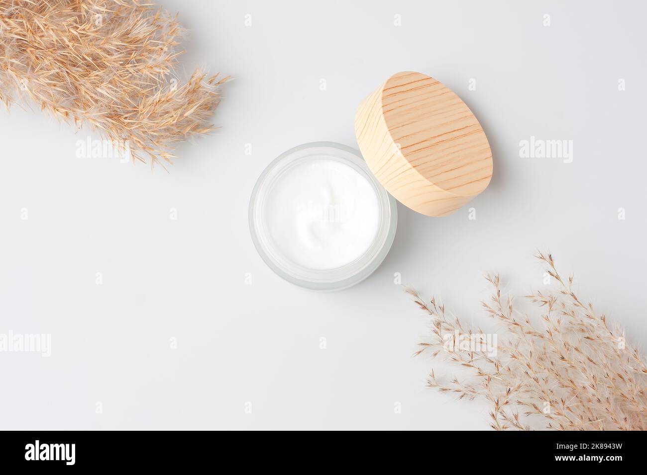 Jar of cosmetic cream with pampas dry grass on white background. Flat lay, copy space Stock Photo