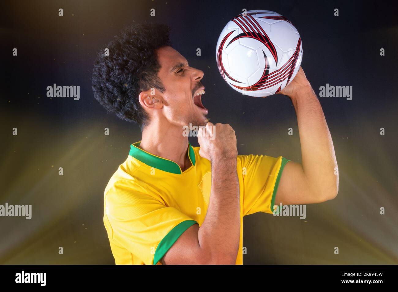 Brazilian Football Black Player Holding Ball and Celebrating, Isolated on Black Background. Stock Photo