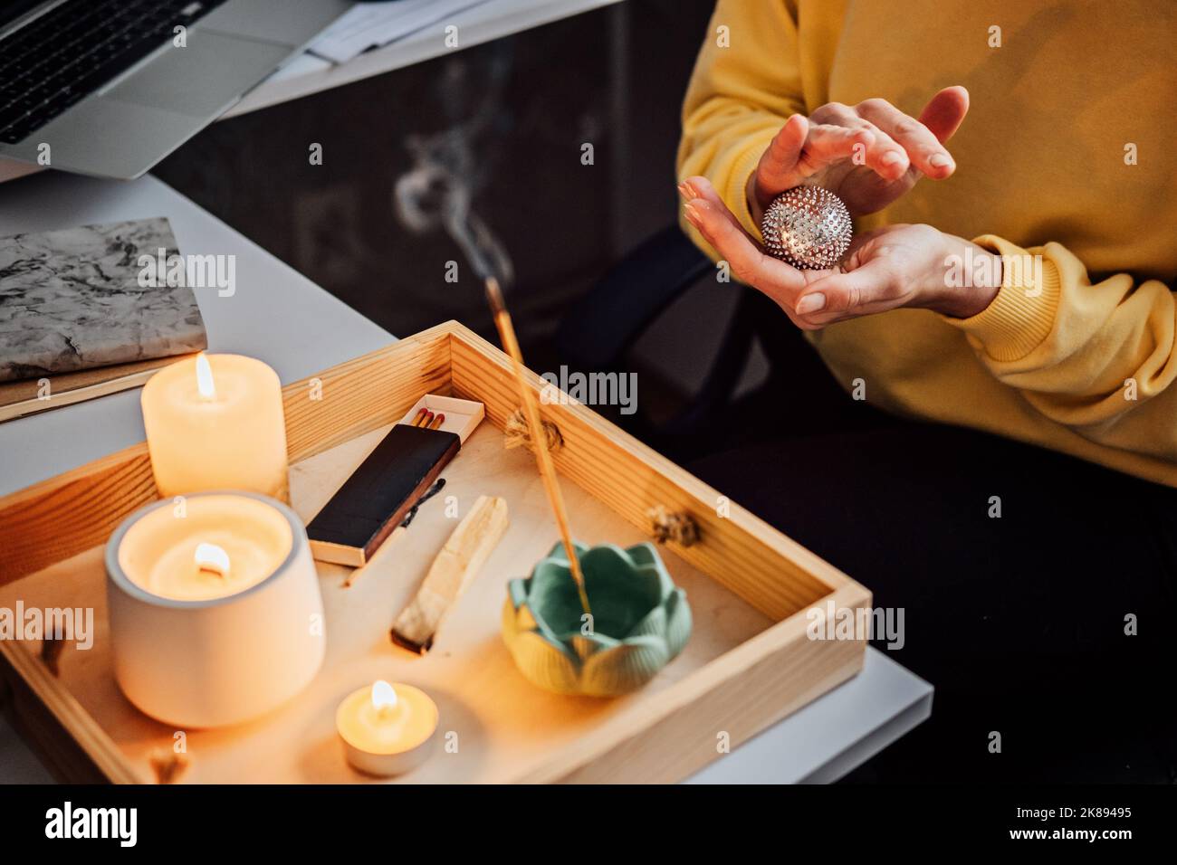 Work life balance. Mental health, mindfulness, wellbeing. Womans hands with massage Acupuncture Su Jok ball near table burning candles and aroma Stock Photo