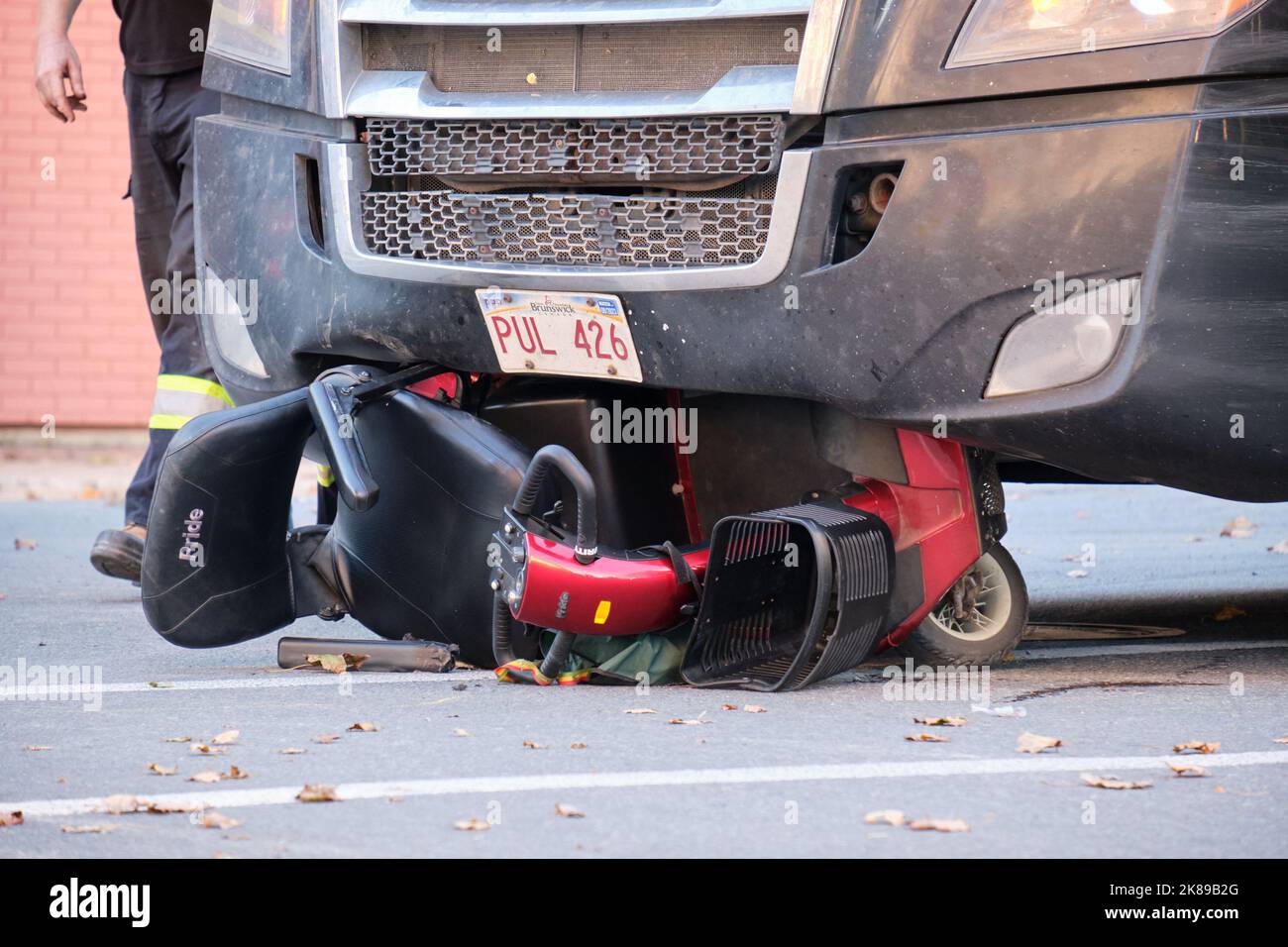 Crushed mobility scooter under the front of large transport truck following accident in Halifax, Nova Scotia Stock Photo