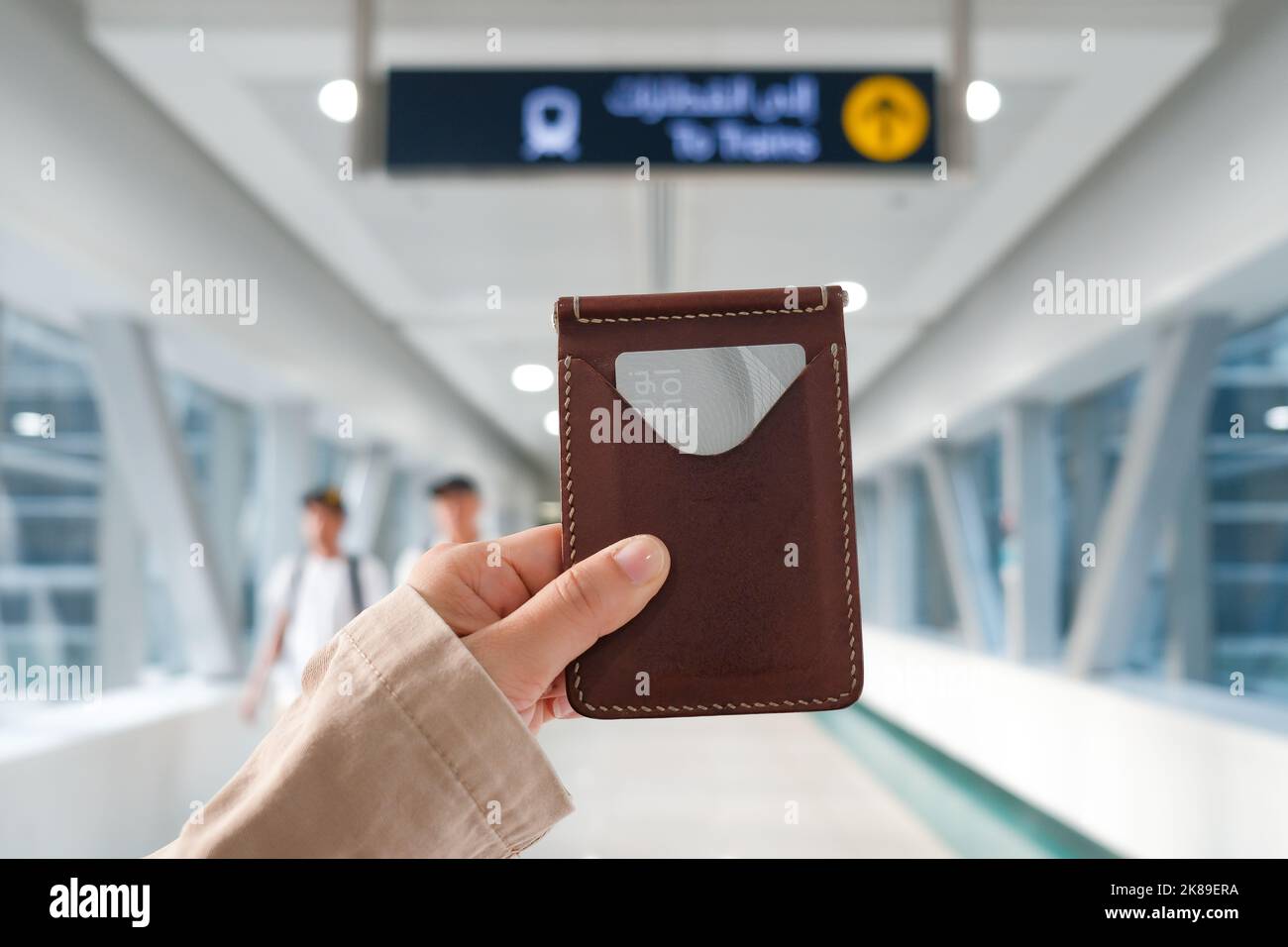 Female hand holds leather card holder with silver Dubai Metro Nol Card