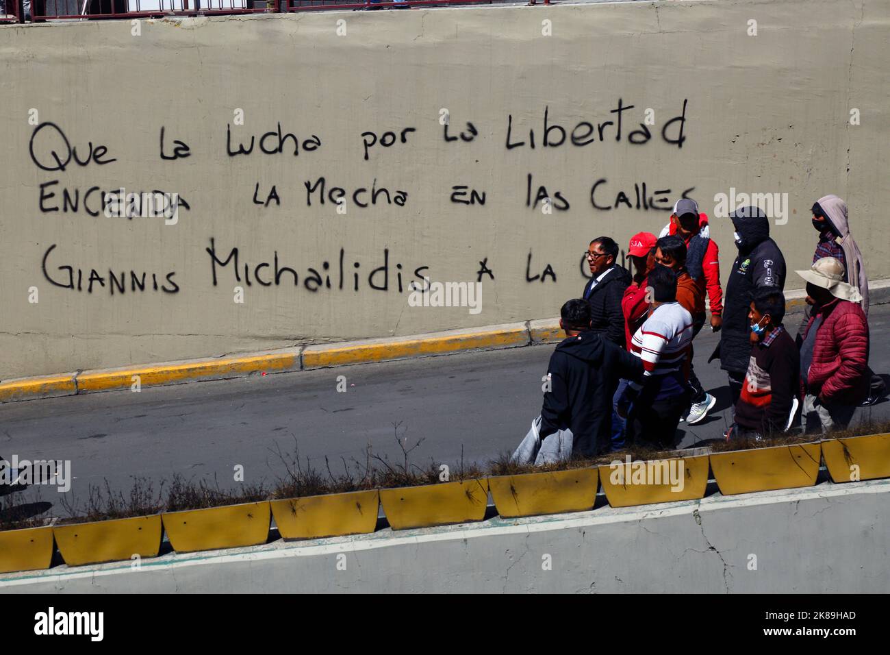 Protesters march pass graffiti in support of Giannis Michailidis, a prisoner in Greece who was on a hunger strike in May-July 2022, La Paz, Bolivia Stock Photo