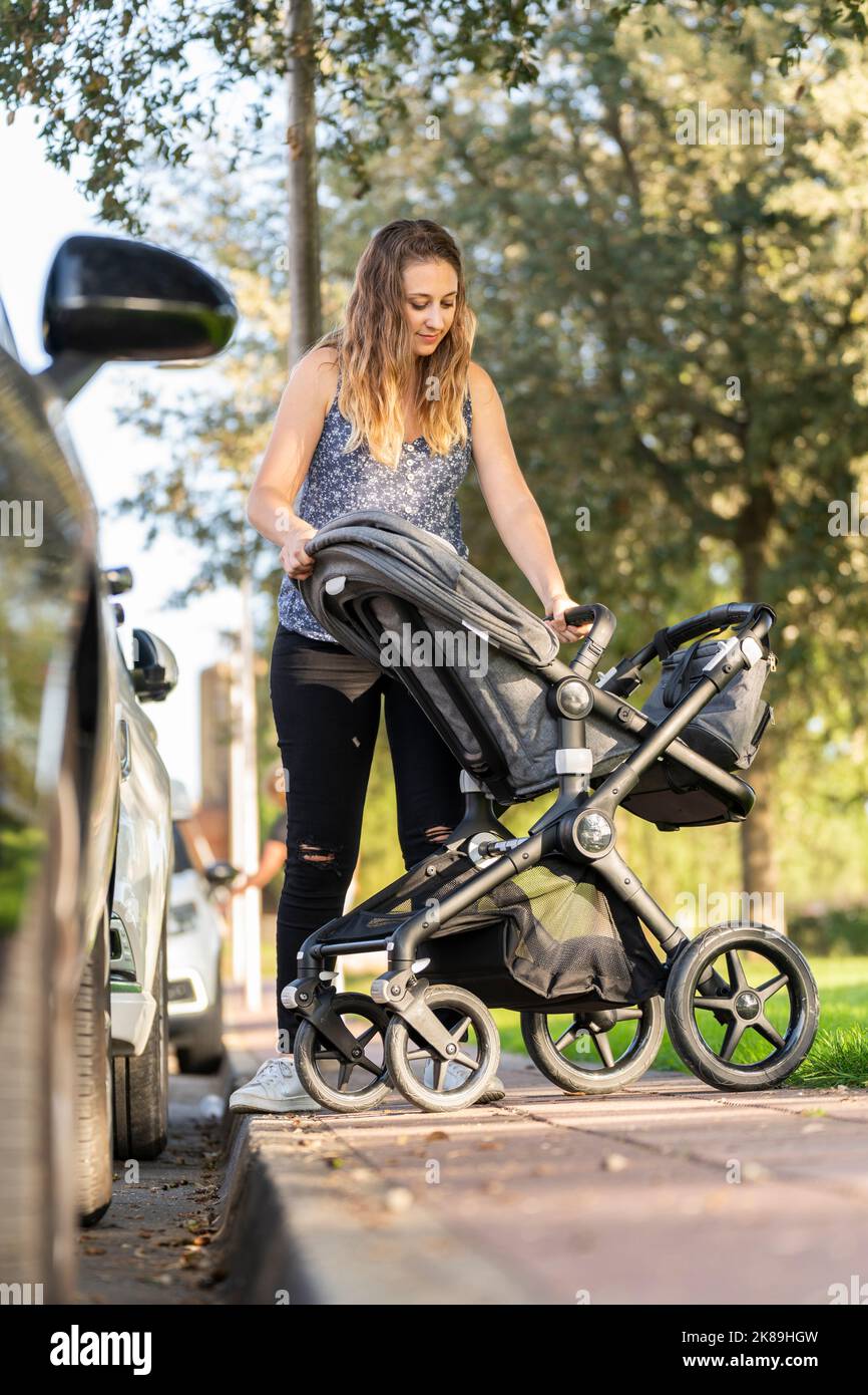 Mother preparing the baby stroller in the park after parking the car Stock Photo