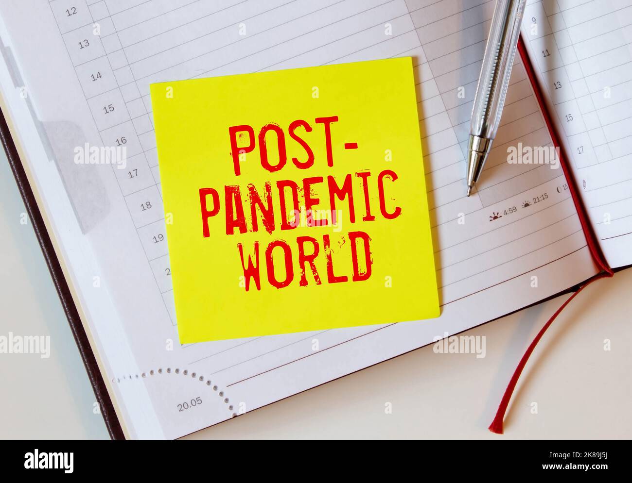 Post-pandemic world symbol. Hand in blue glove with white card. Concept words 'Post-pandemic world'. Metalic pen. Medical and COVID-19 pandemic post-p Stock Photo