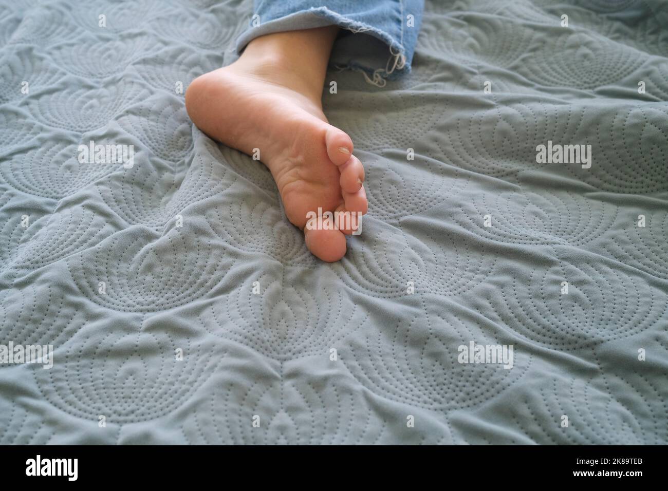 female foot on bed cover Stock Photo