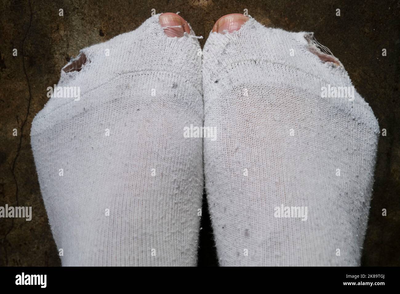 Man toes poking through holes in white socks, hardship concept Stock Photo