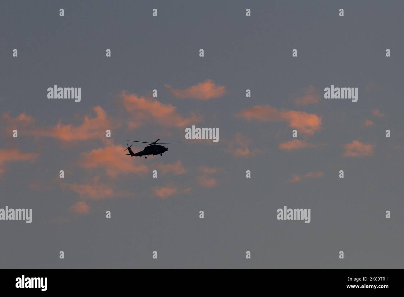 A silhouette of a Sikorsky SH-60 Seahawk helicopter with the United Stated Navy (USN flying in front of sunset clouds near NAF Atsugi airbase, Kanagaw Stock Photo