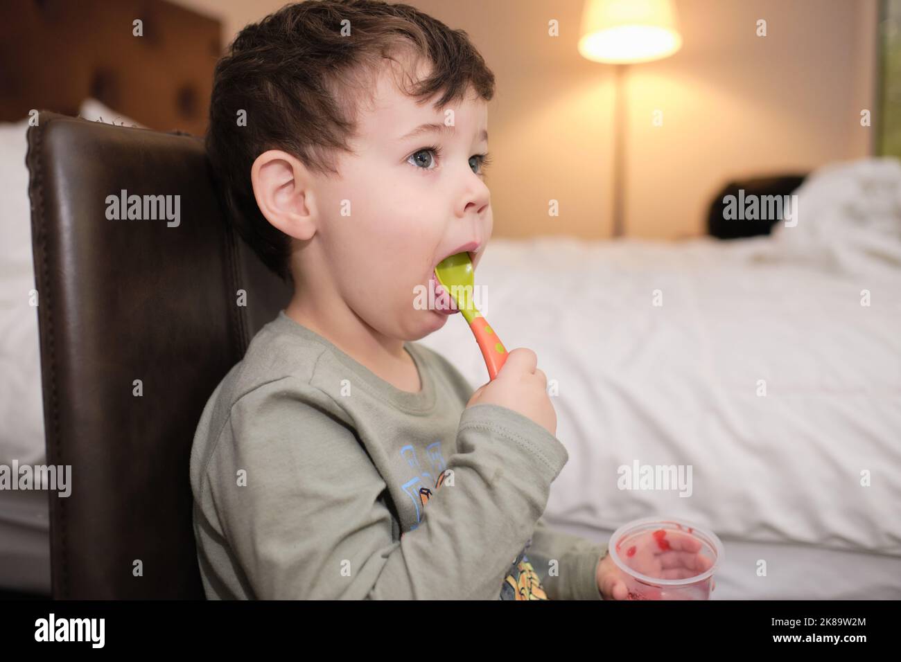 cute expressive young boy is eating a gelatin snack while watcching TV