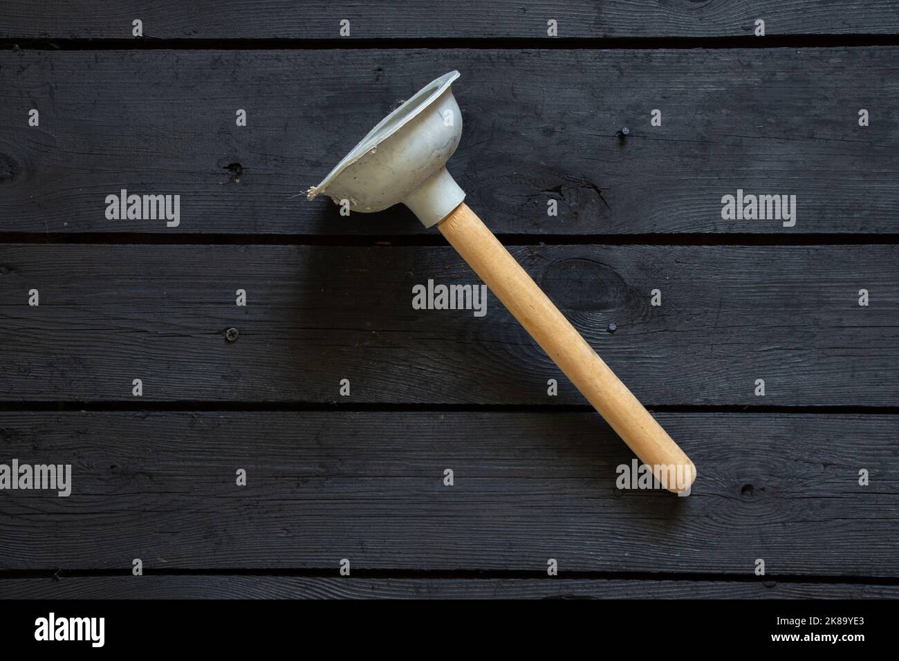 new rubber plunger on black wooden surface, plumber repair, toilet bowl cleaning Stock Photo