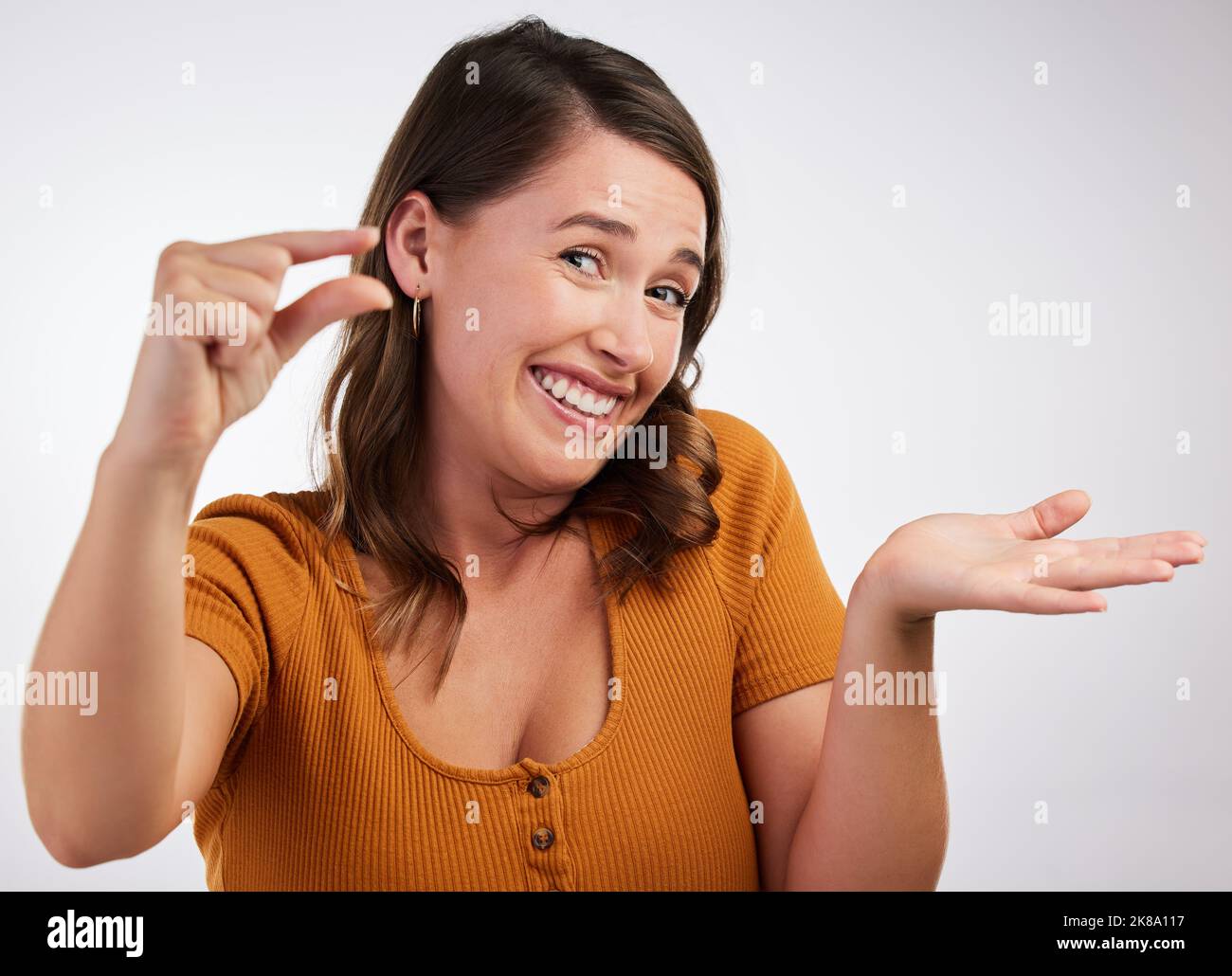 This is the amount of money I have left. Studio shot of a young woman gesturing a small size with her hand against a white background. Stock Photo