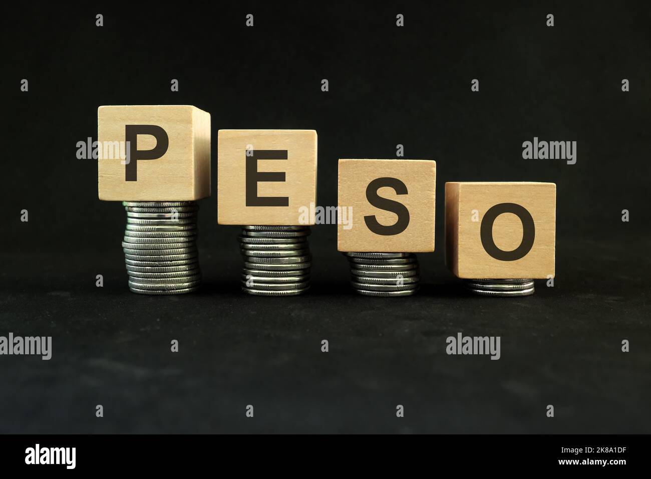 Philippine peso weakening, value depreciation and devaluation concept. Decreasing stack of coins on dark black background. Stock Photo