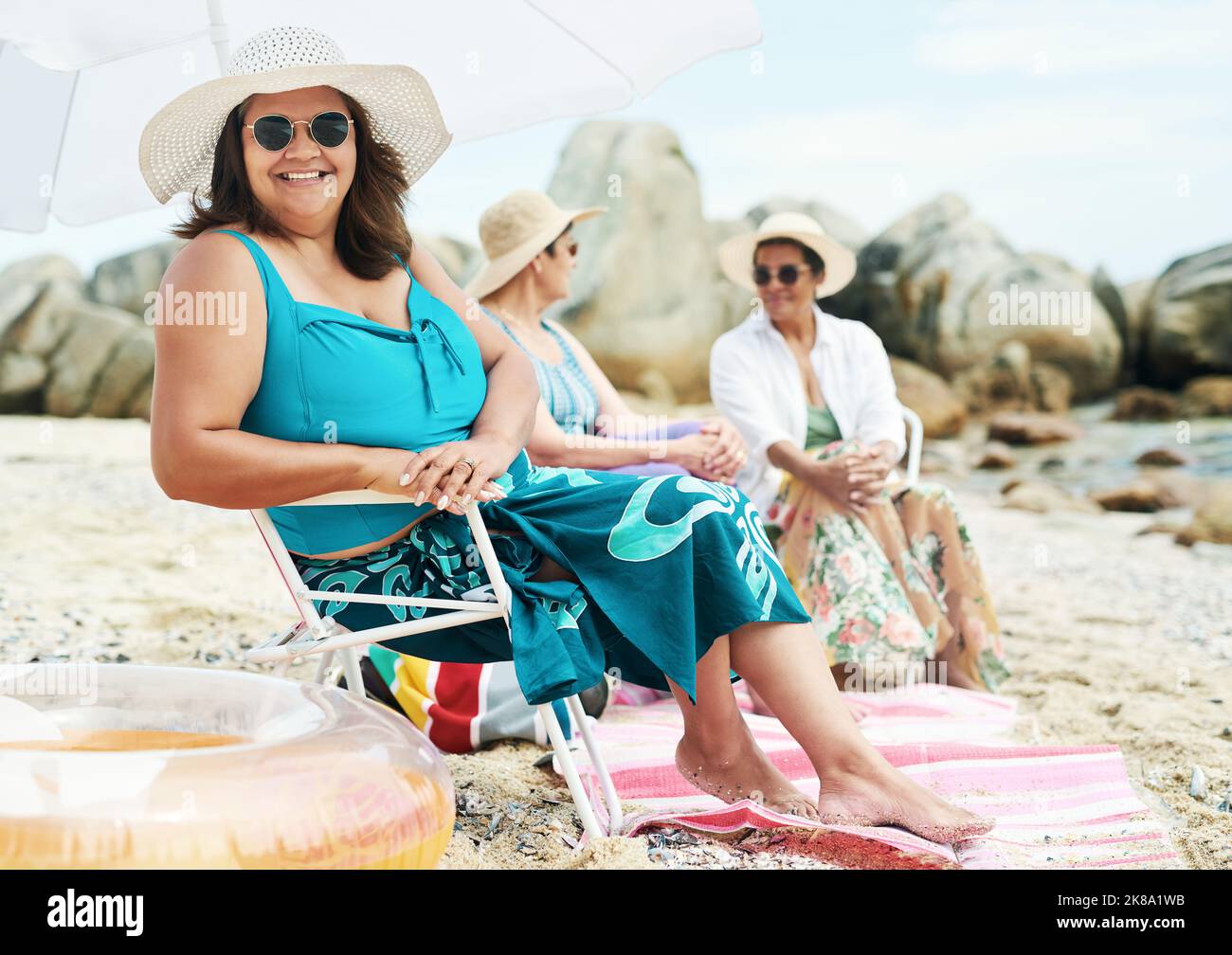 Enjoy freedom in a one piece and on the beach. a mature woman sitting and enjoy a day out on the beach with friends. Stock Photo