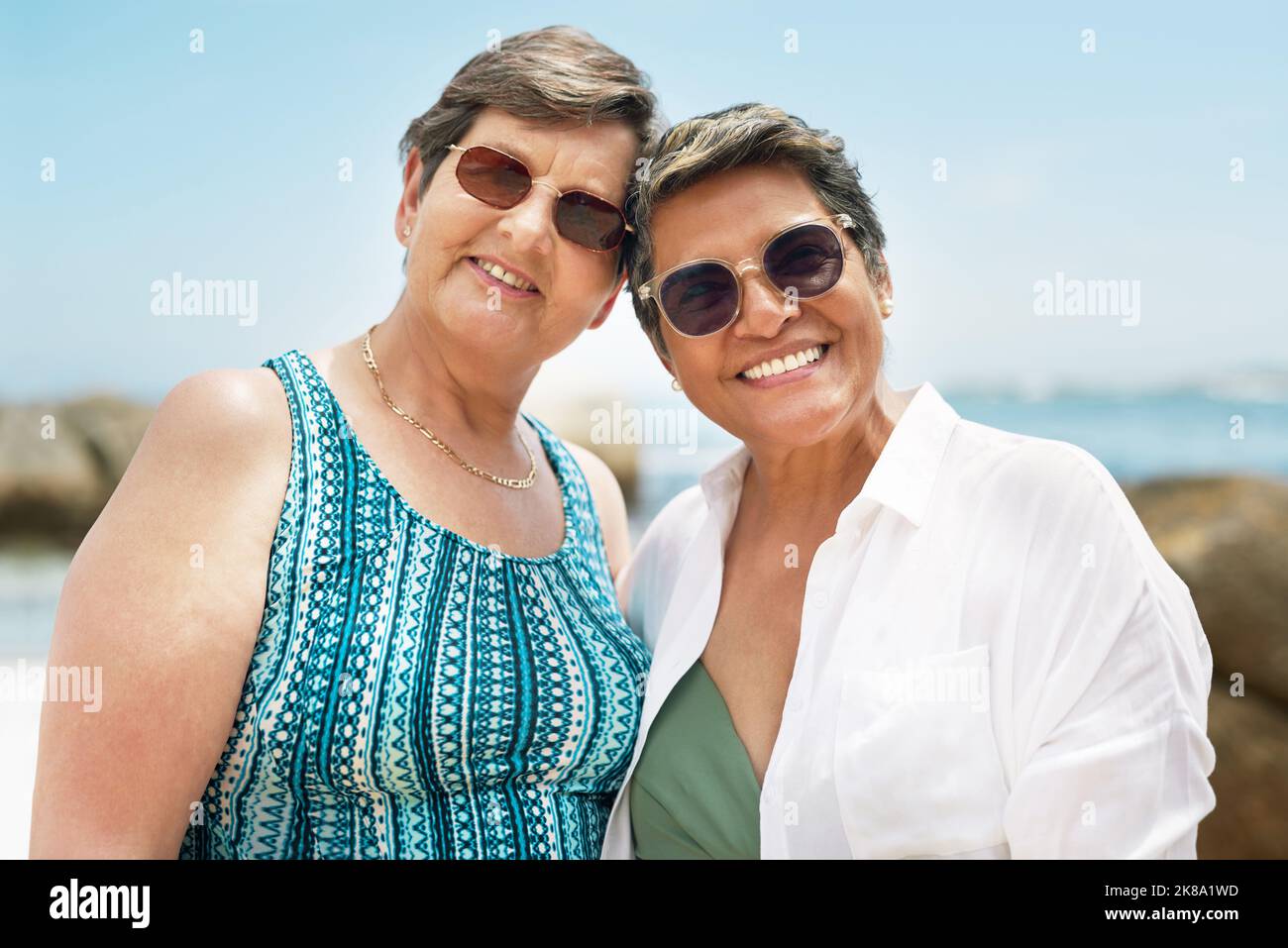 Heres to ageing gracefully with my best friend. two mature friends standing together during a day out on the beach. Stock Photo