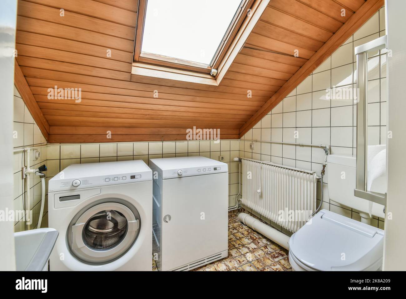 Wall hung toilet and small sink in corner in lavatory room with washing