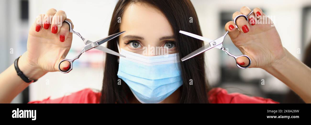 Young qualified master holding pair of scissors for work and posing in ...