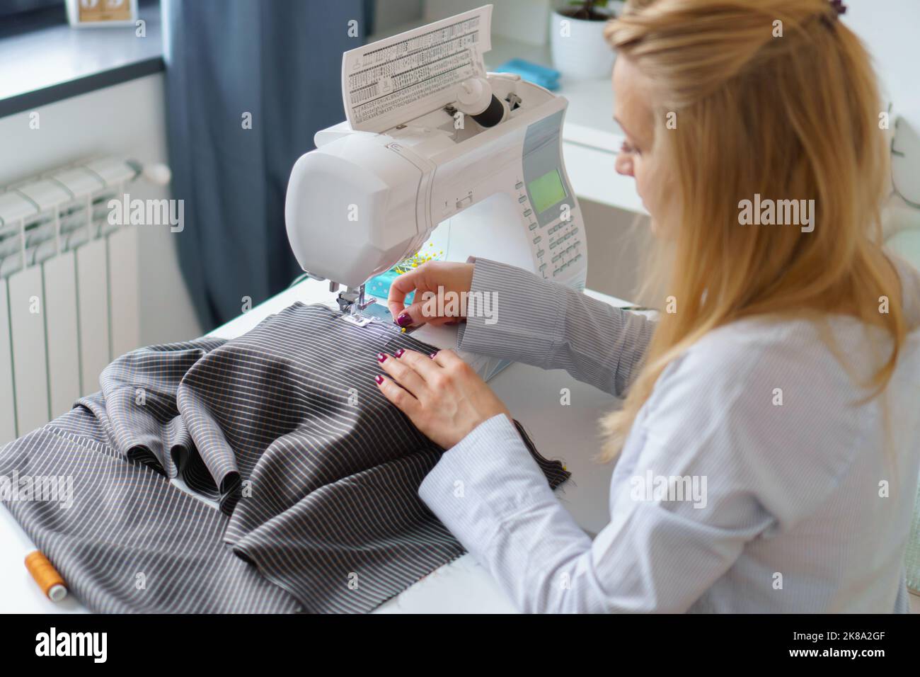 Seamstress woman works on sewing machine. Dressmaker hands work at sewing factory Stock Photo