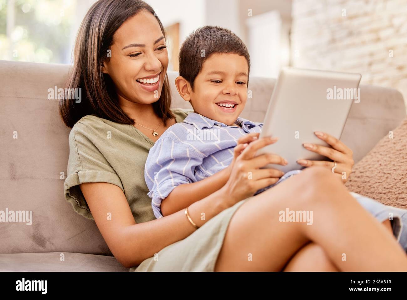 Family, digital tablet and mother and son relax on sofa, bond and laugh at online game, movie or cartoon. Happy family, child and parent watching Stock Photo