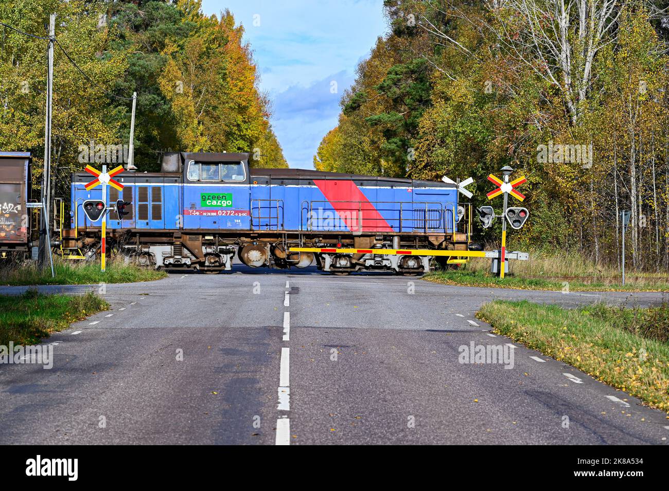 crossroad with trainset passing over asphalt road Stock Photo