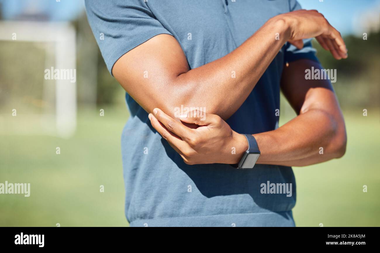Sports man with elbow pain on arm, injury in outdoor soccer field. Hand massage bone, person with emergency muscle problem, physiotherapy in sport and Stock Photo