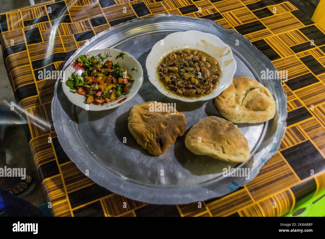 Traditional meal in Sudan - fuul (stew of cooked fava beans), salad and bread. Stock Photo
