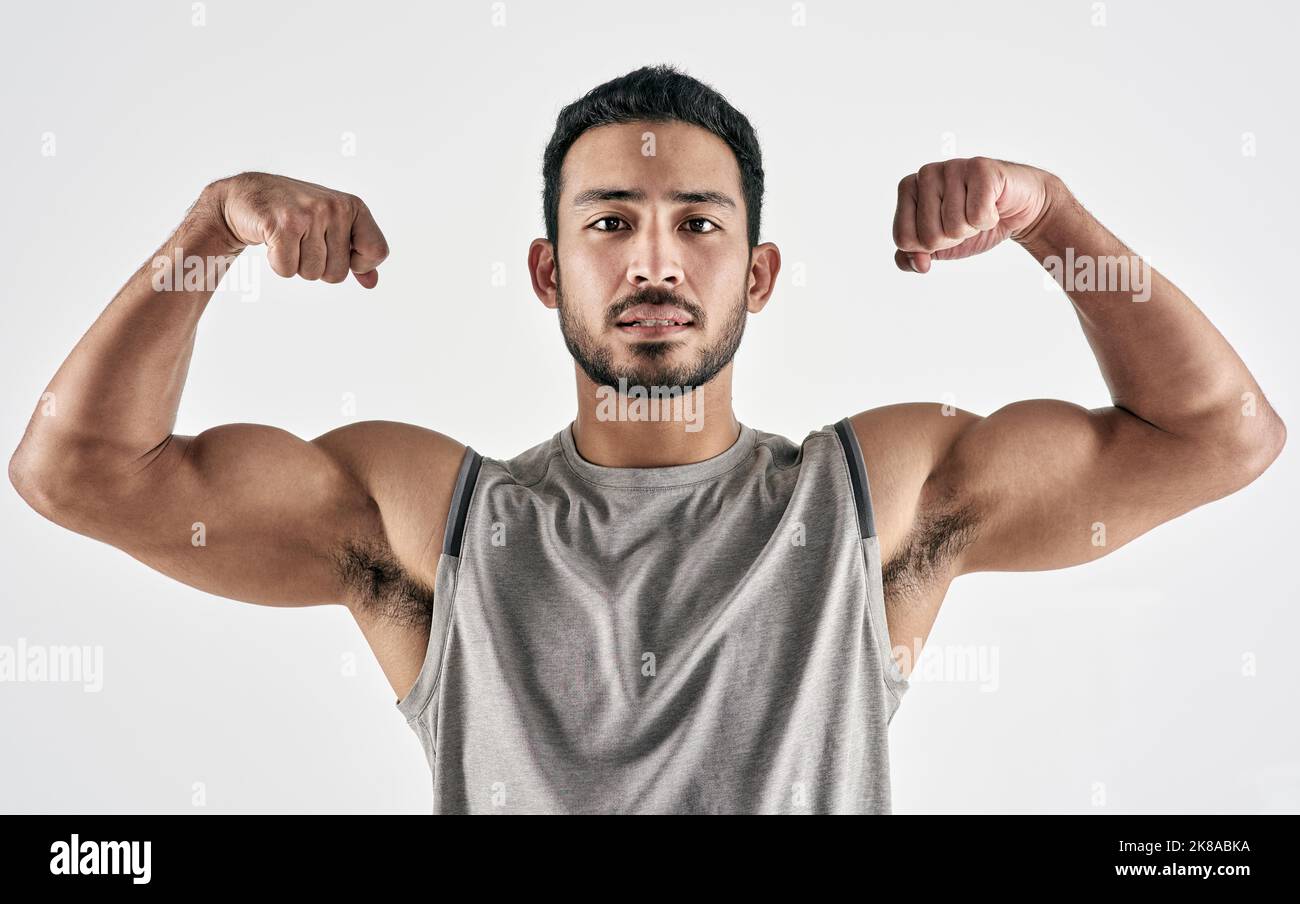 All is earned, not given. Studio portrait of a muscular young man flexing his biceps against a white background. Stock Photo