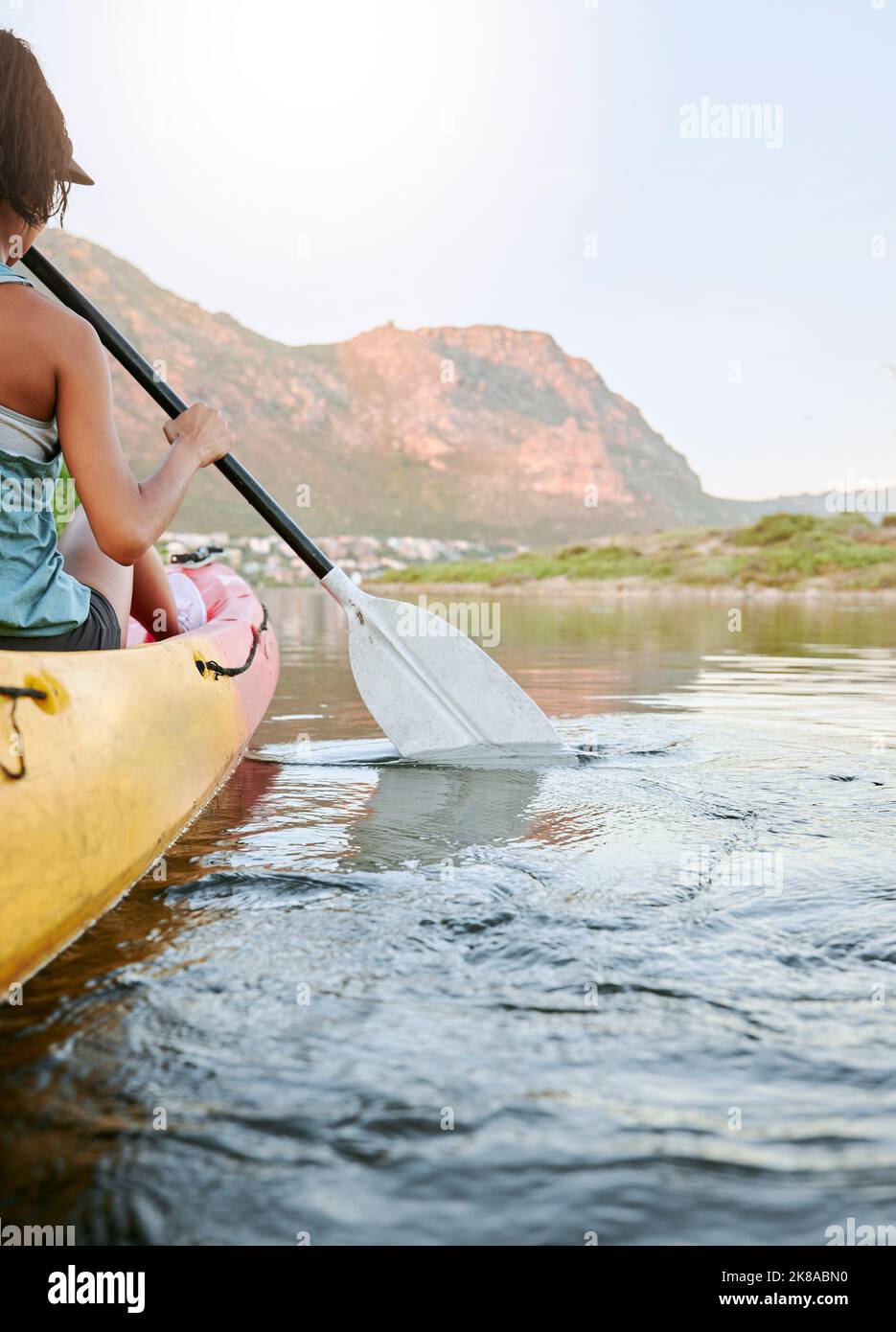 Woman rowing a kayak or boat on a river or lake while on summer