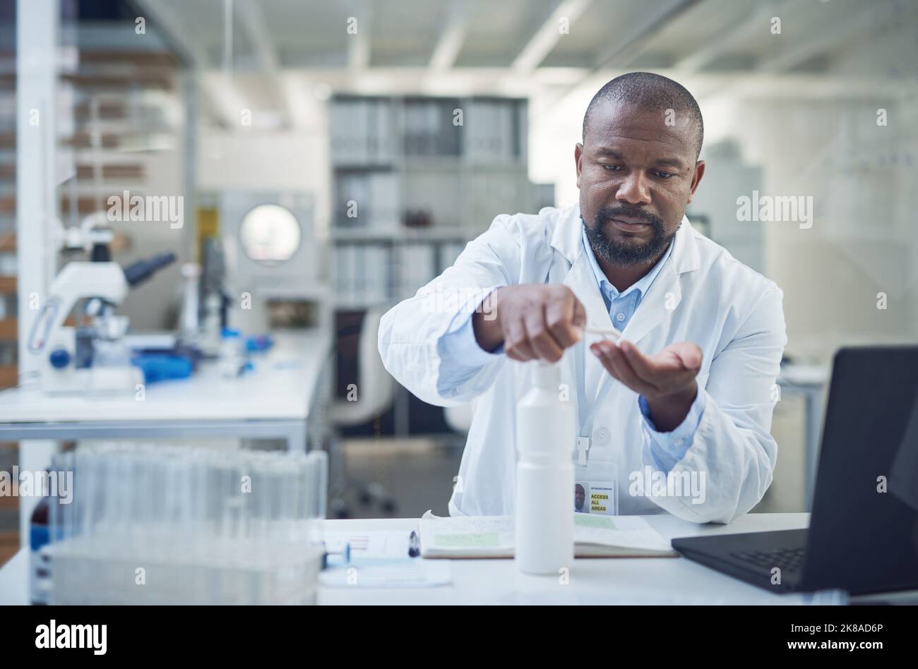 We cure disease, we dont spread them. a scientist disinfecting his hands while conducting research in a laboratory. Stock Photo