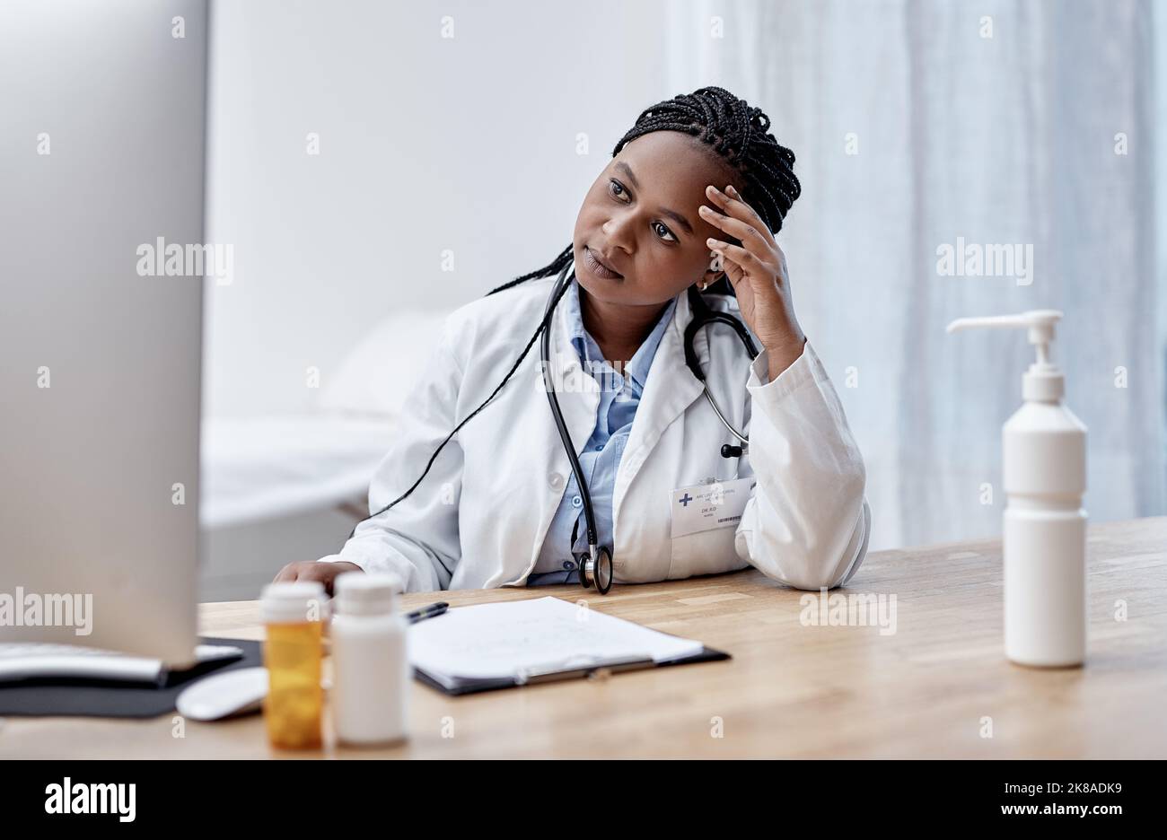 Doctors are humans too. a young doctor looking worried while working on a computer in her office. Stock Photo