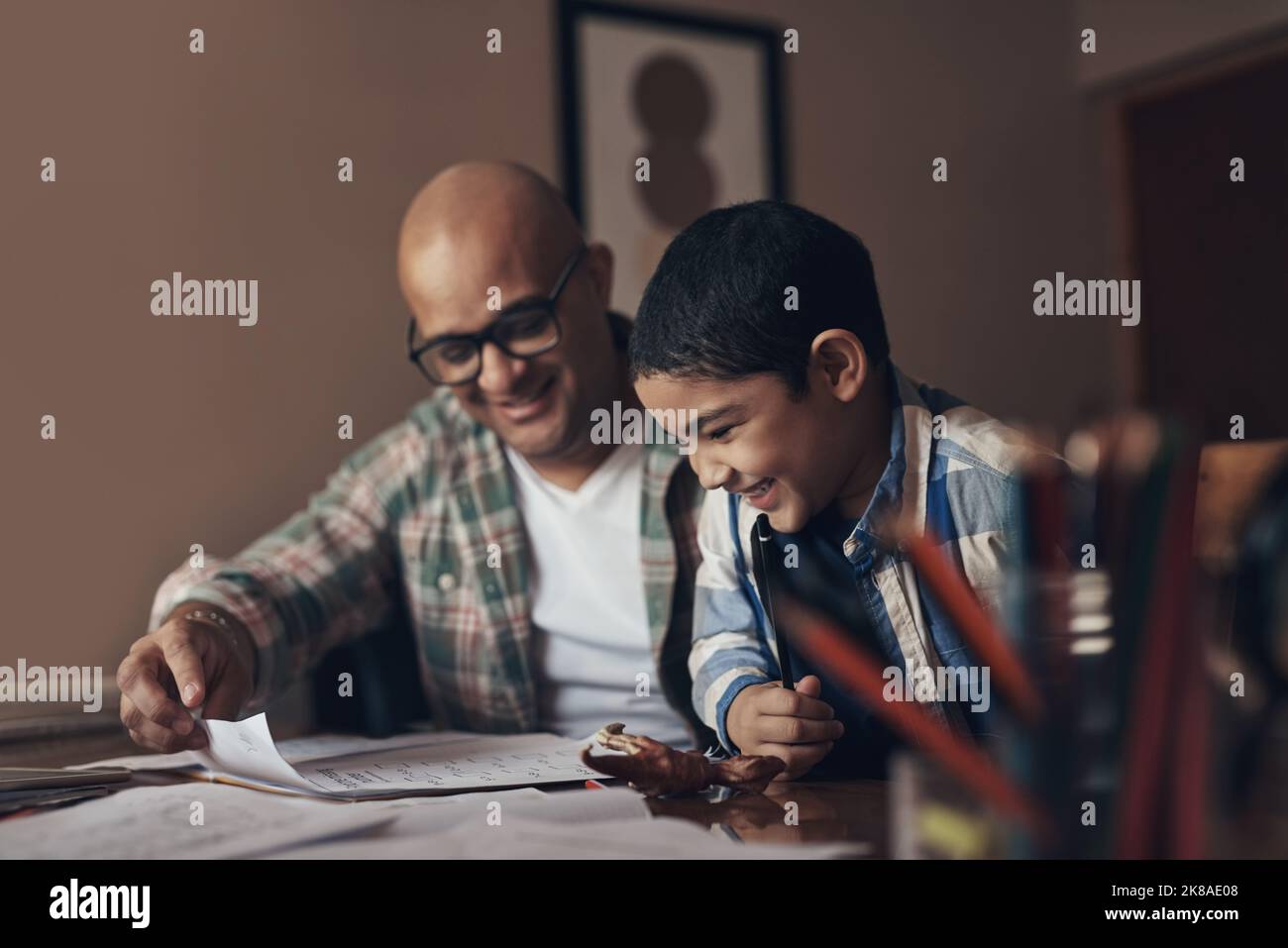 Quarantine promoted many parents to teachers. an adorable little boy completing a school assignment with his father at home. Stock Photo