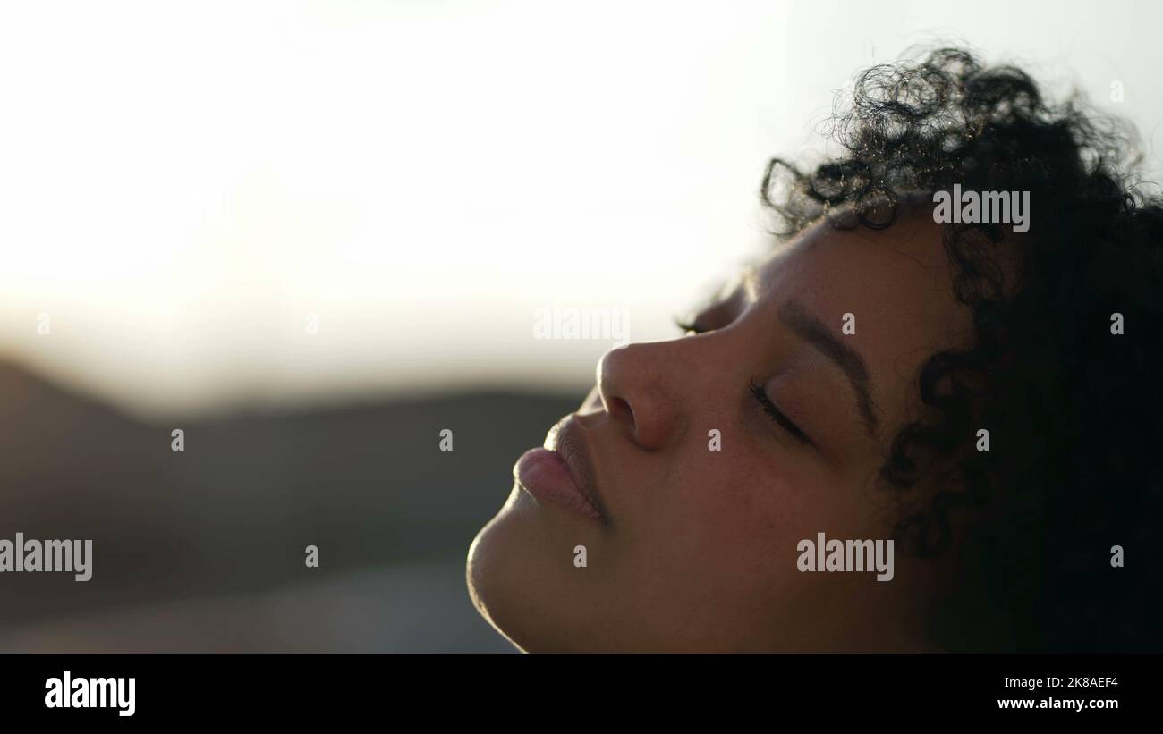 Meditative African American closing eyes in contemplation. A carefree black girl opening eye to