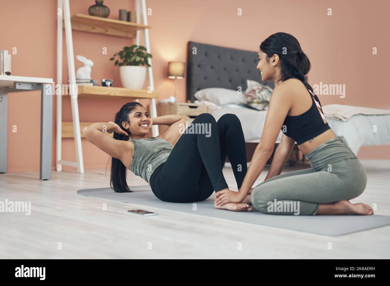 My sister is my biggest supporter. two beautiful young women exercising together at home. Stock Photo