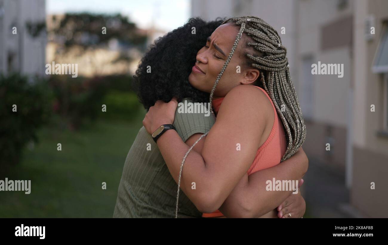 Young woman consoling tearful female friend giving an empathic hug. Girlfriends sharing anxious problems in crisis. Two Brazilian people embrace Stock Photo