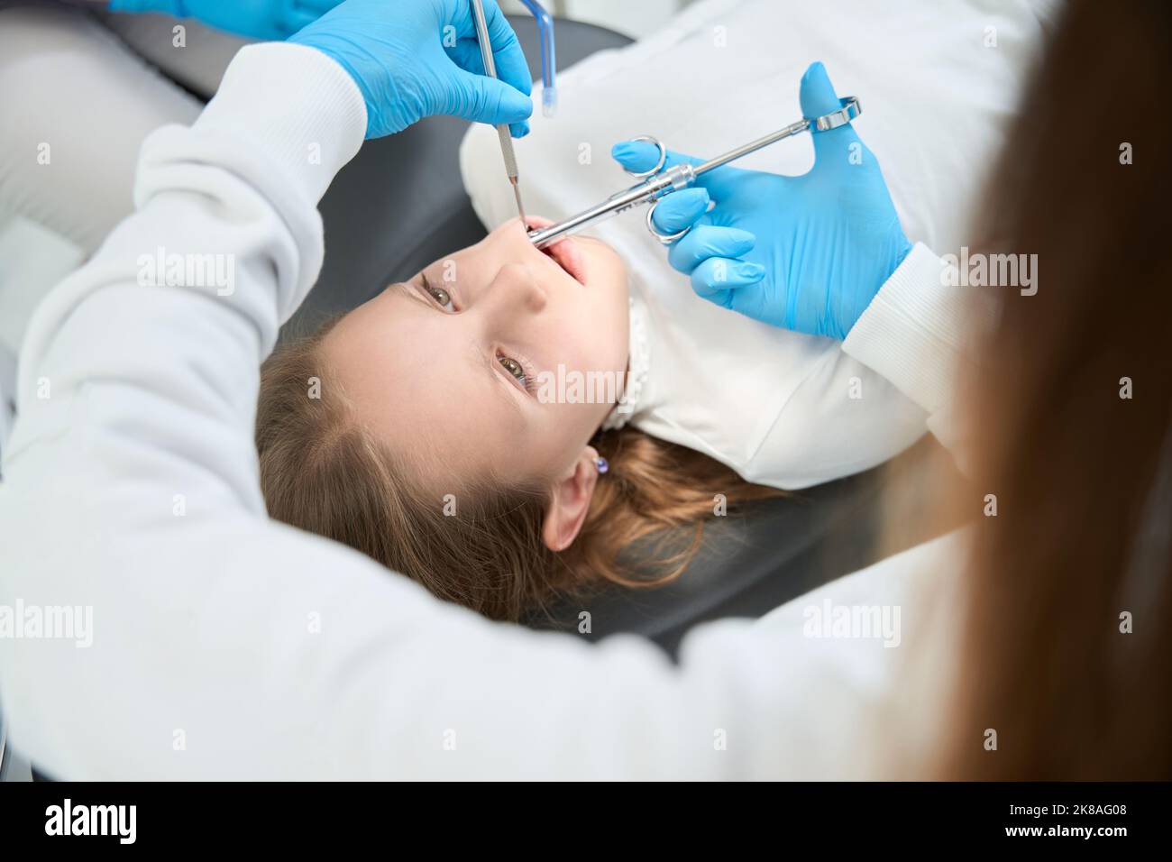 Pediatric dentist giving local anesthesia to child with dental syringe