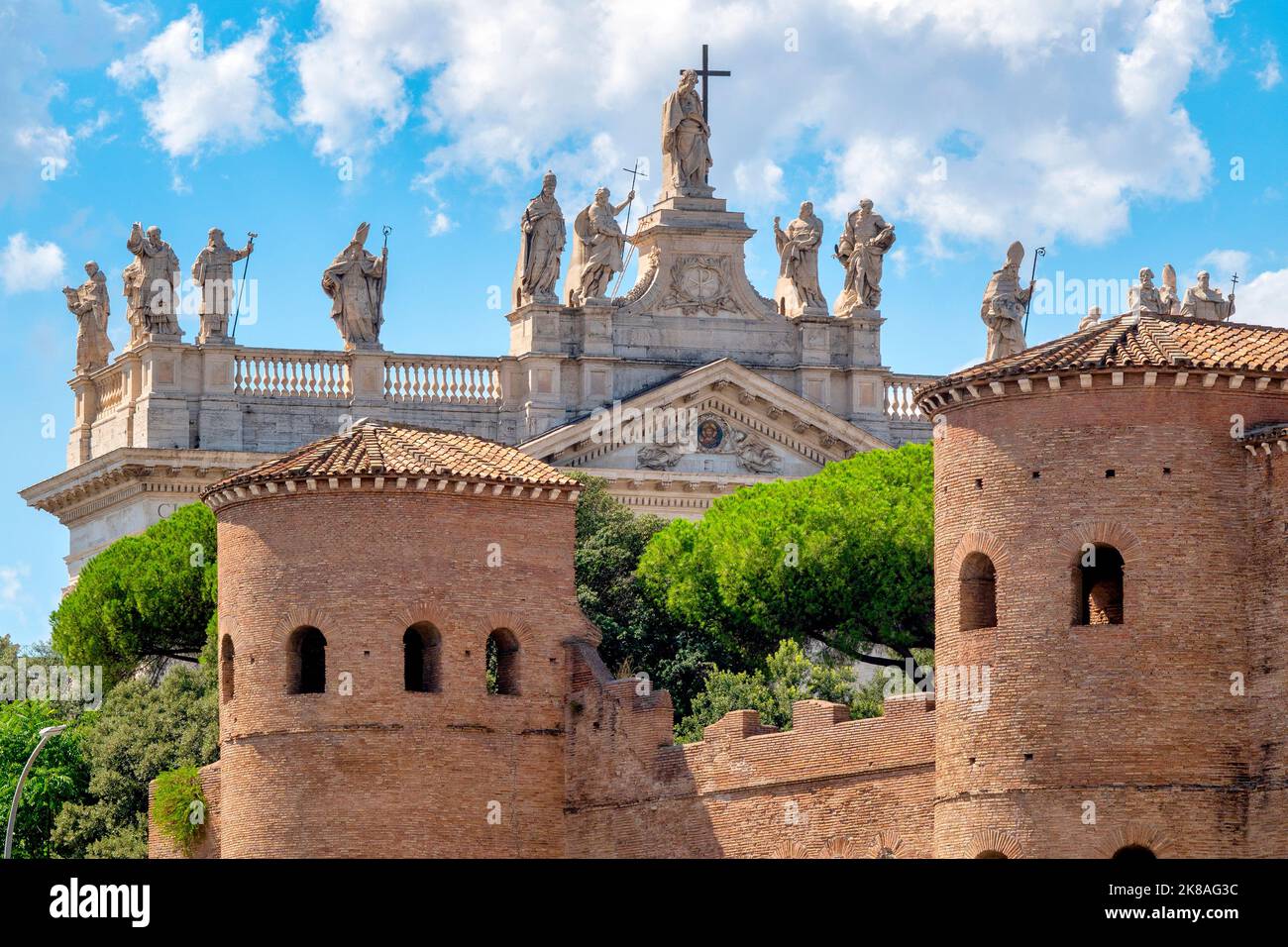 Towers of the Aurelian walls near Porta San Giovanni with the facade of the Archbasilica of San Giovanni in Laterano in the background, Rome, Italy Stock Photo