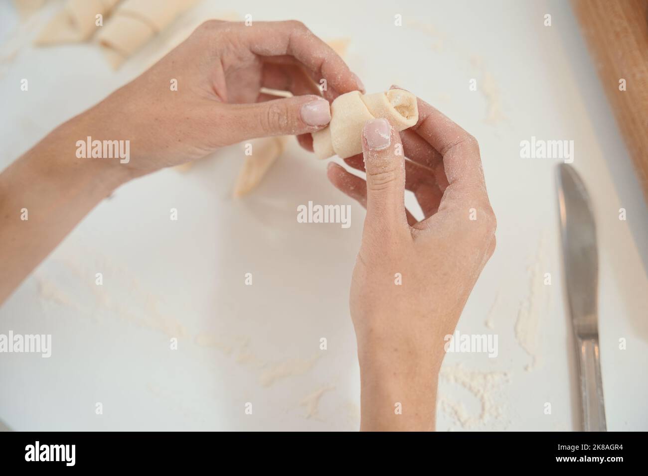 Woman in hands holds a croissant blank from cooked dough Stock Photo