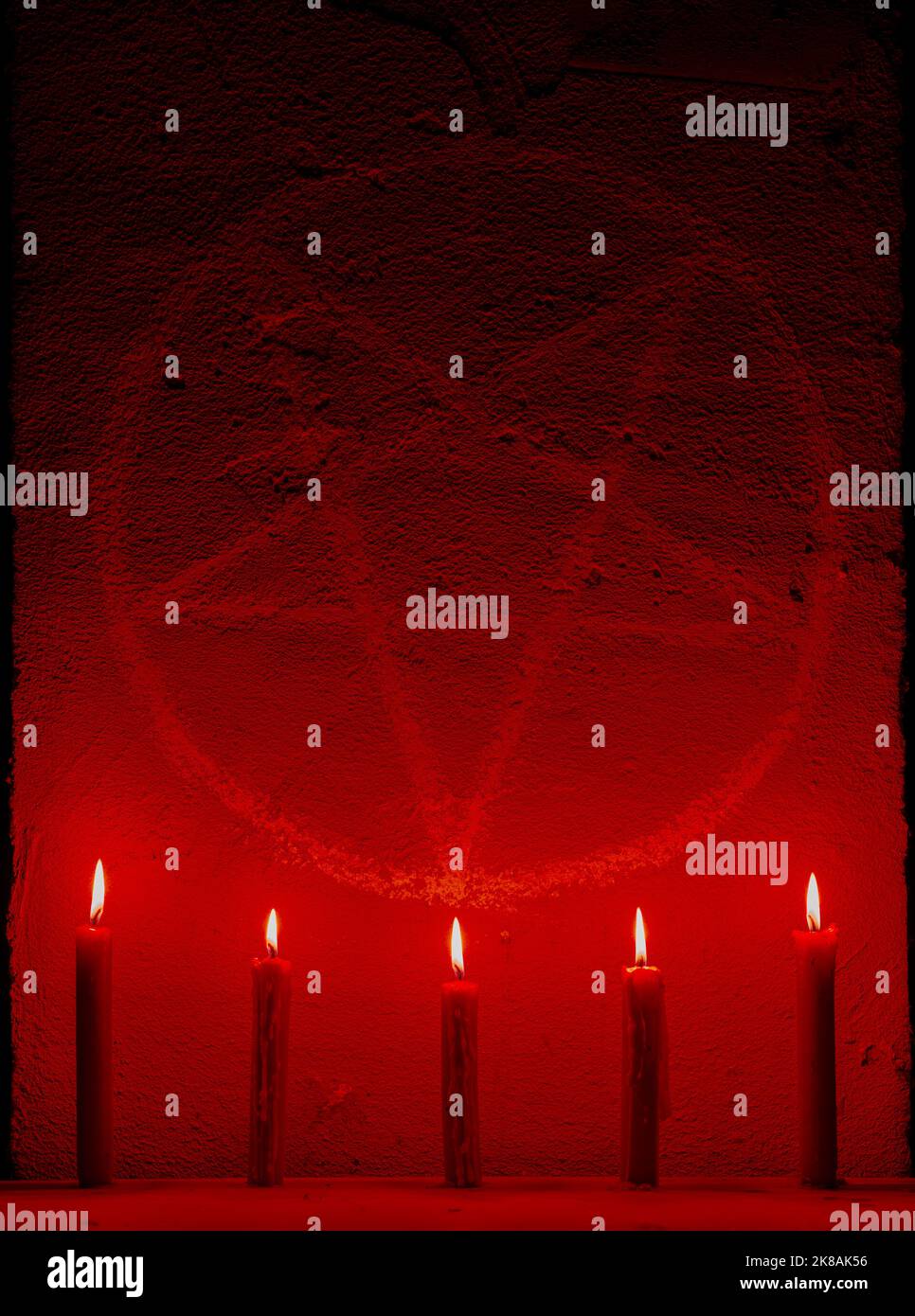 White pentagram symbol on concrete wall. Satanic altar illuminated with candles. Dark background. Scary, mystical occultism Stock Photo