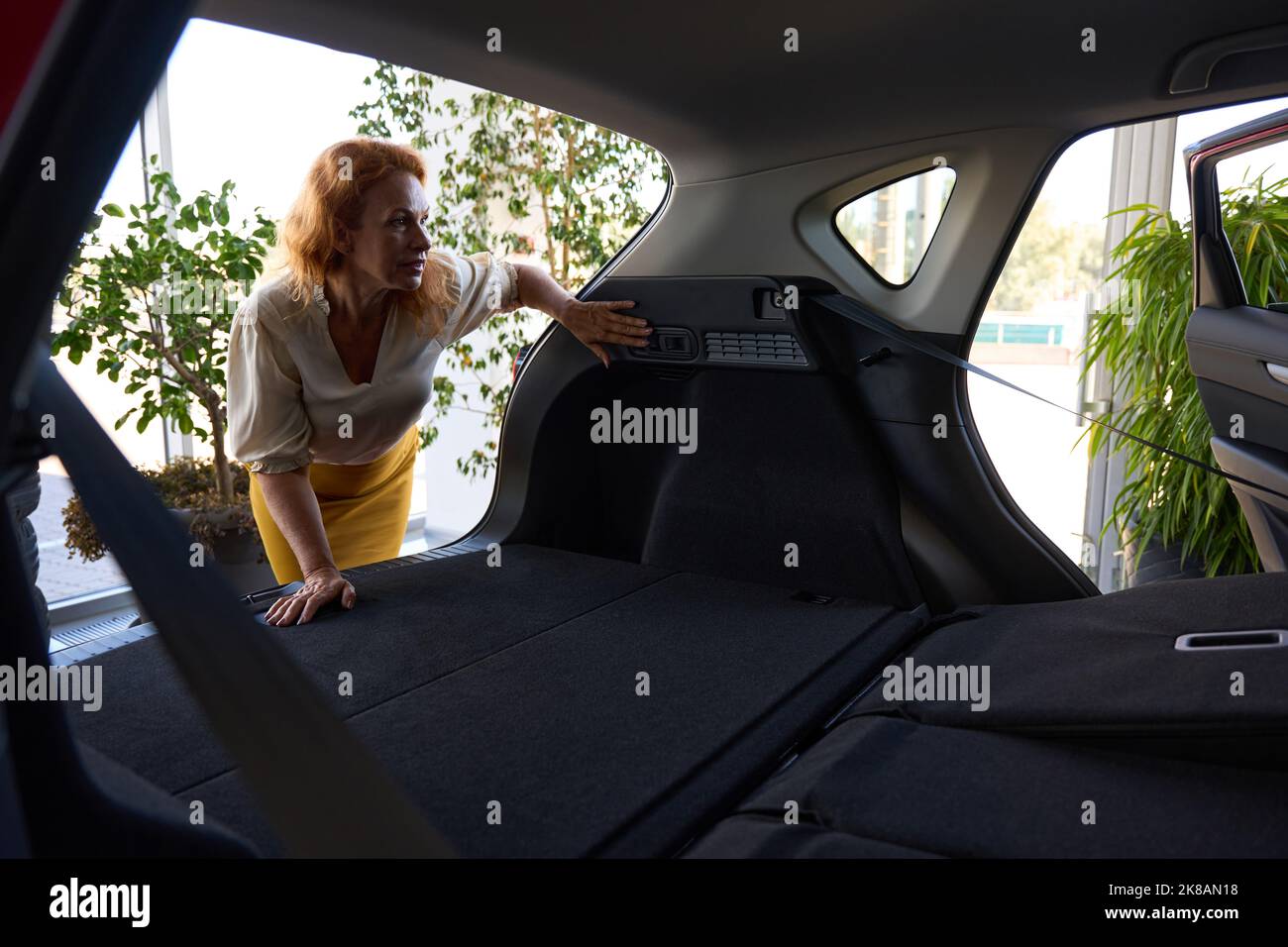 Serious female person thinking about buying red car Stock Photo Alamy