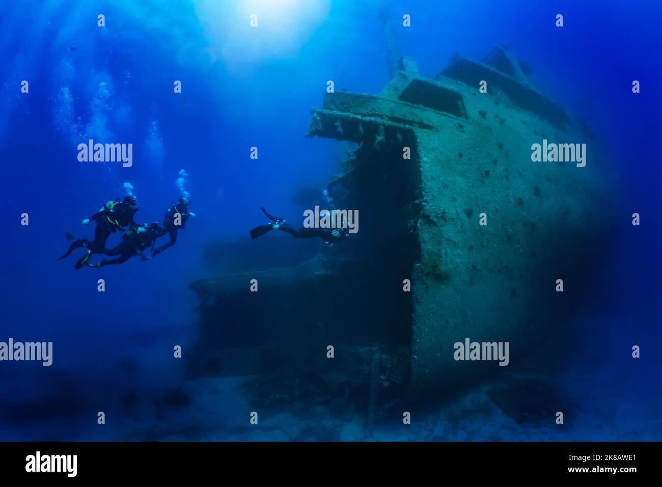 A diving instructor leads a group of divers through a big shipwreck Stock Photo