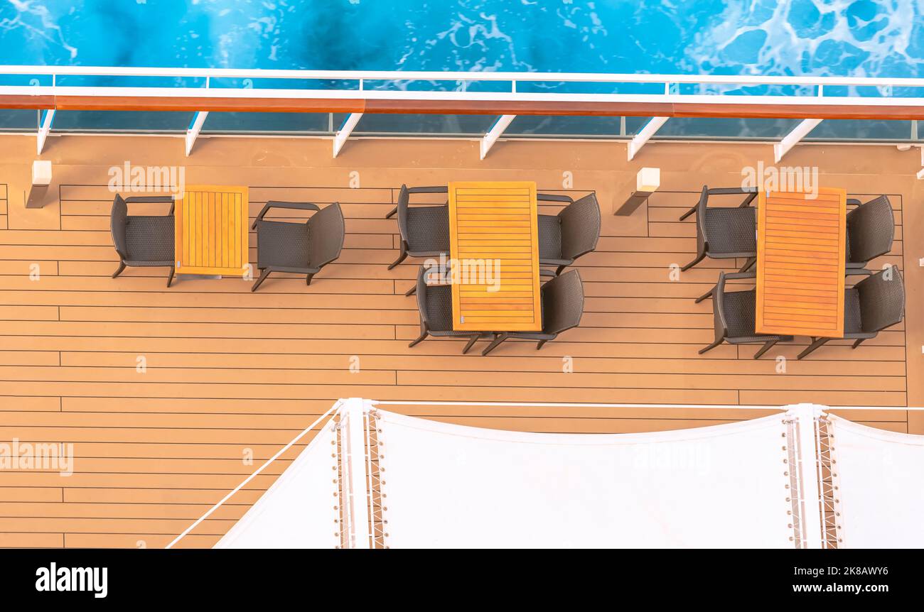 View of tables and chairs on a deck of a cruise ship sailing with the
