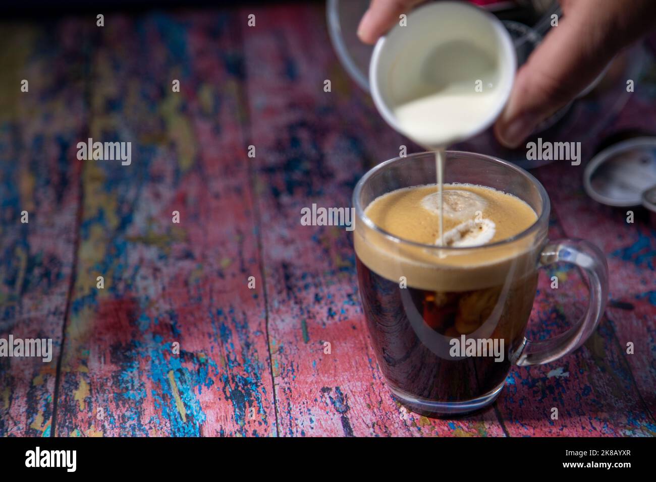 Americano With Cream Being Poured Into Drink Stock Photo