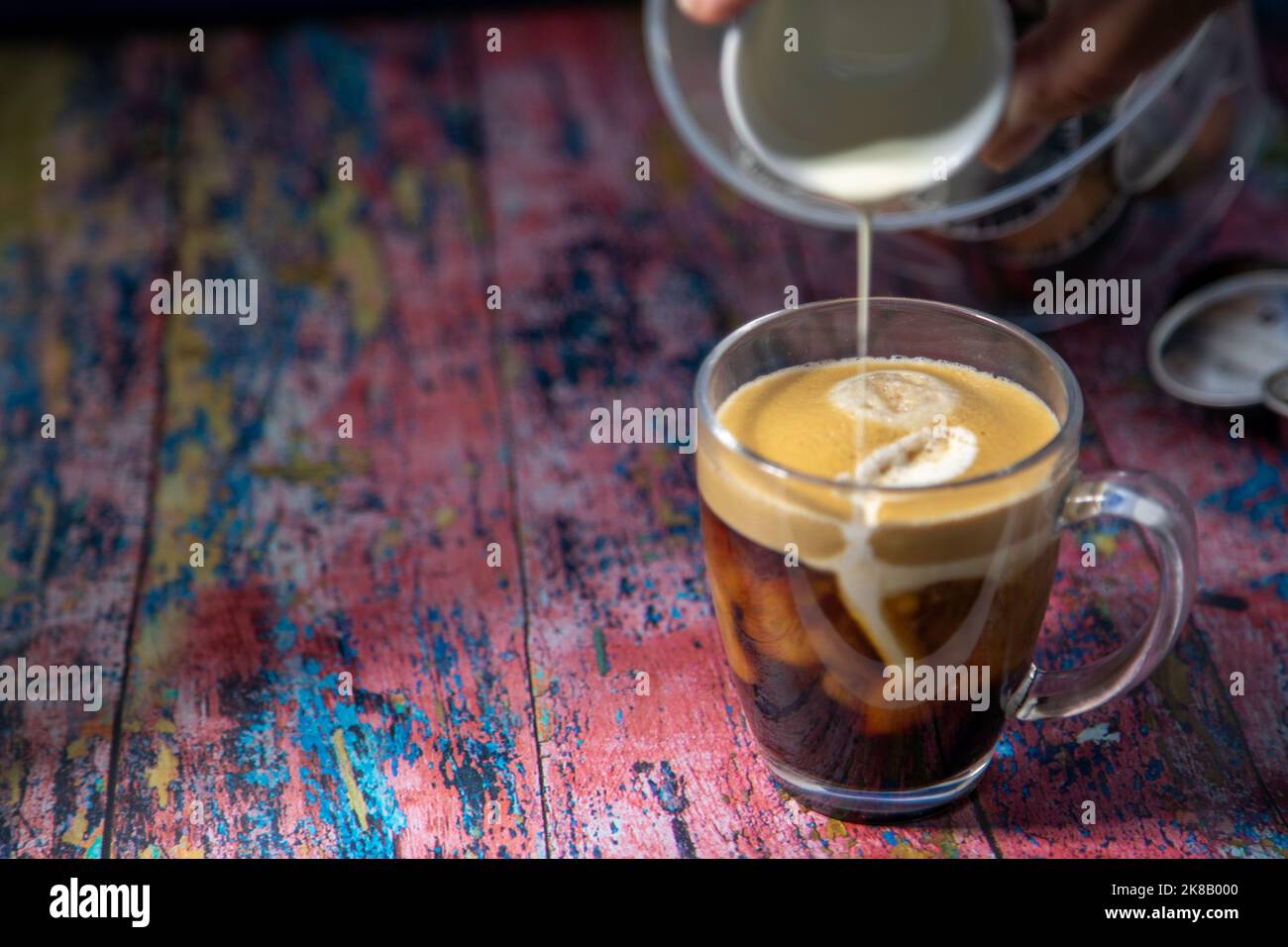 Americano With Cream Being Poured Into Drink Stock Photo
