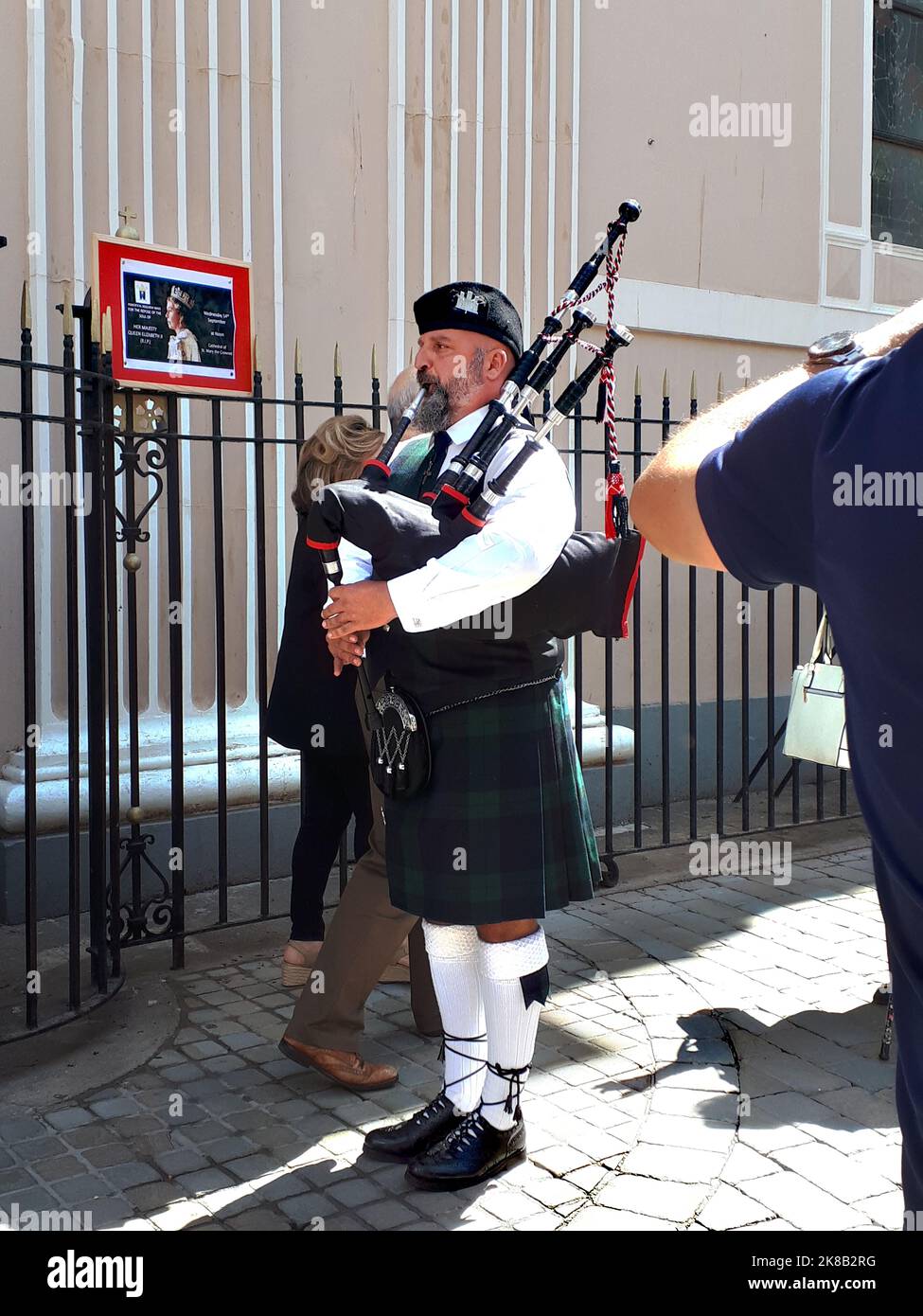 Scottish Piper playing a lament as people exit from a funeral Mass for
