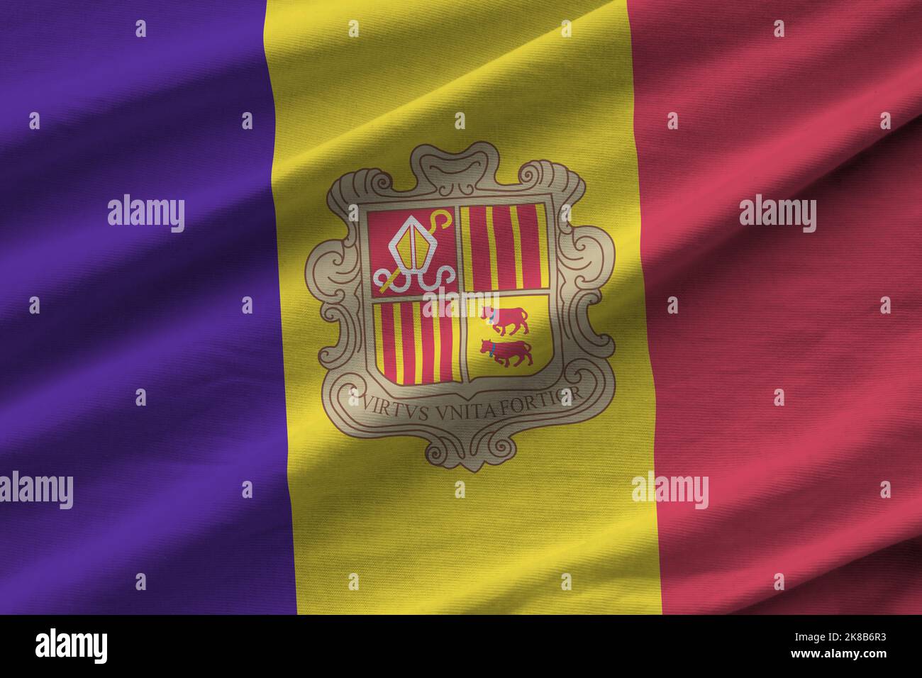 Andorra flag with big folds waving close up under the studio light indoors. The official symbols and colors in fabric banner Stock Photo