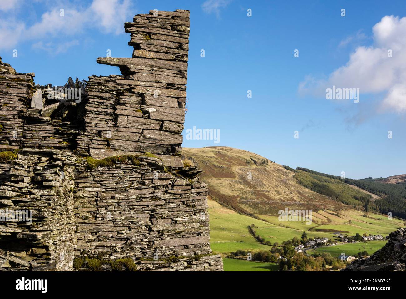 Old ruined building in disused Rhiw Fachno quarry with village in valley beyond. Cwm Penmachno, Betws-y-Coed, Conwy, north Wales, UK, Britain Stock Photo