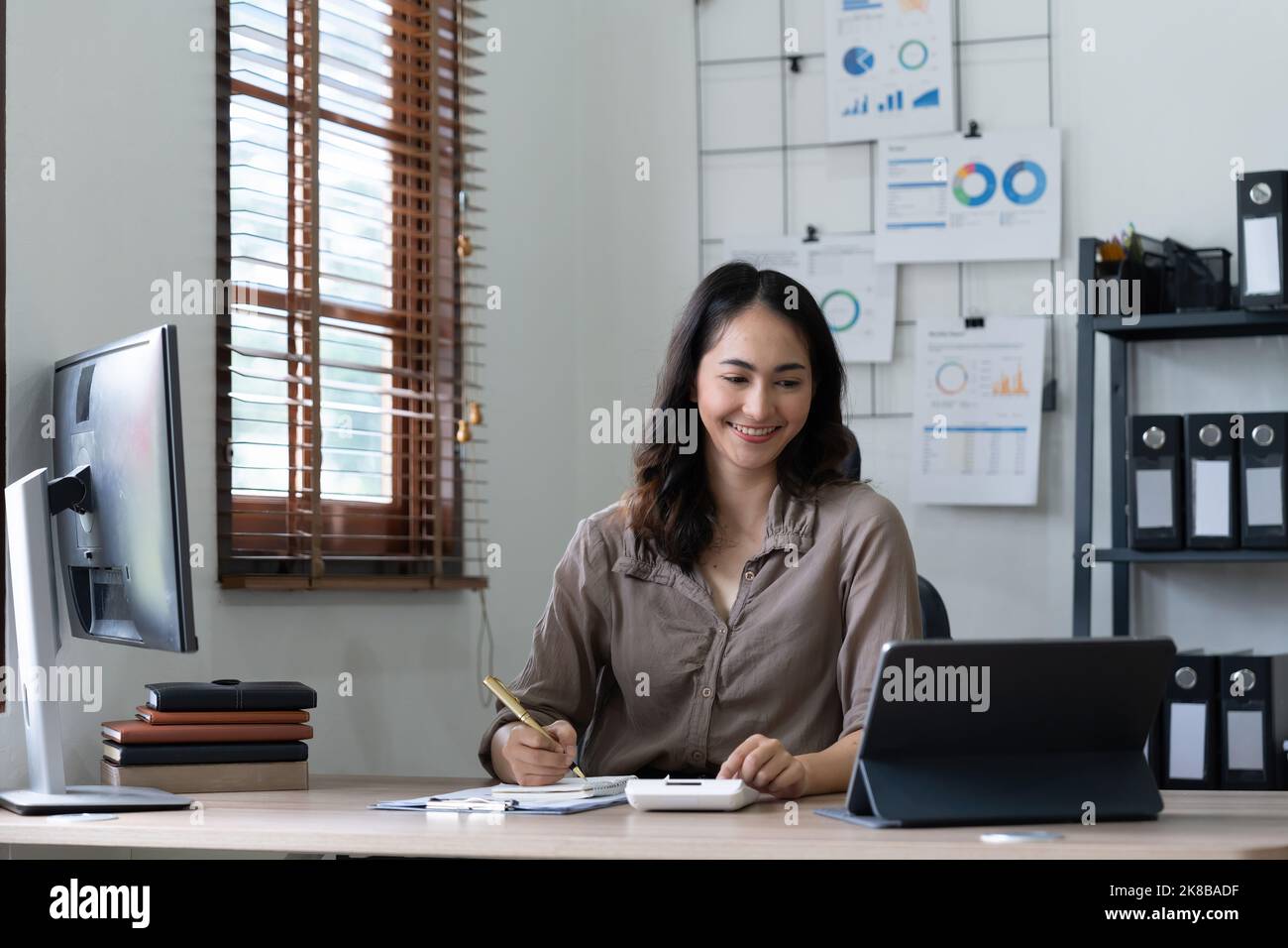 Asian woman accountant preparing annual financial report checking result on calculator bookkeeping. female freelancer counting tax rates declaring Stock Photo