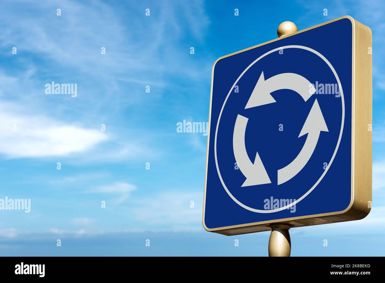 Close-up of a blue and white roundabout road sign against a clear blue sky with clouds and copy space. Europe, Photography. Stock Photo
