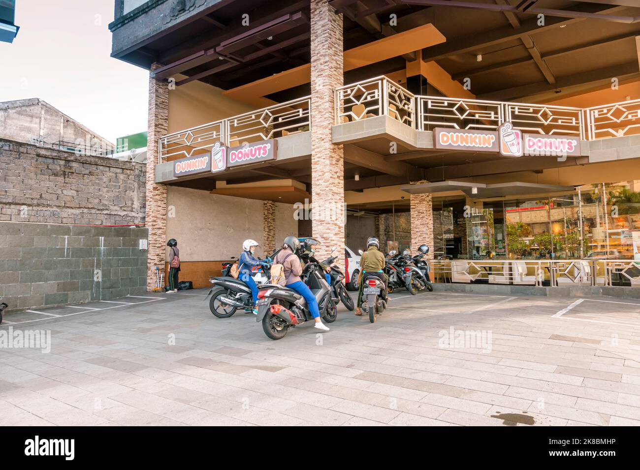 Group of youngsters on mopeds stopped close to Dunkin Donuts coffee. Denpasar, Indonesia - January 8, 2020 Stock Photo